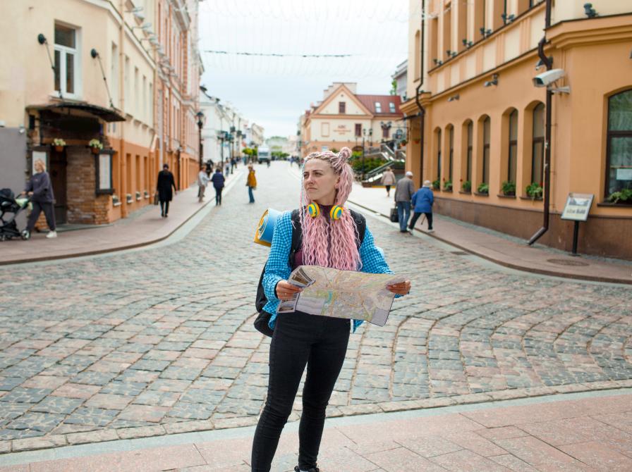 kvindelig ung turist står med et kort i en fremmed by